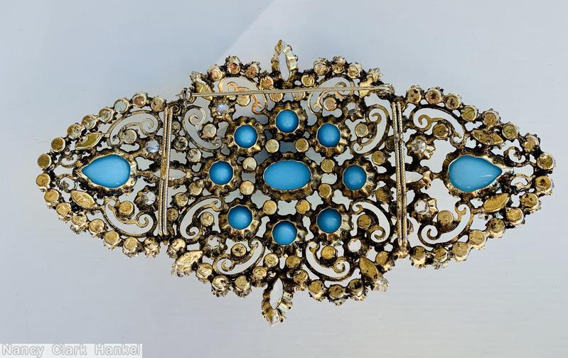 Schreiner diamond shaped radial scrollwork buckle bordered small invert stone oval cab center 8 surrounding round cab 2 large teardrop at end opaque baby blue round cab crystal inverted goldtone jewelry