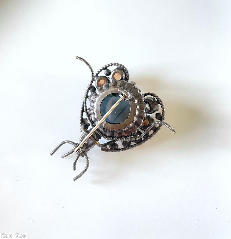 Schreiner bug 2 wing 4 whisker large round stone body 2 curly wire leg each wing 7 varied size stone 2 small chaton eye small oval stone head rose cut smoky blue large round stone topaz inverted faceted chaton peridot eye small chaton silvertone jewelry