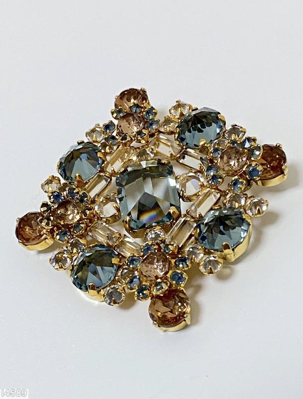 Schreiner diamond shaped radial pin elongated hexagon center stone 4 large round cab 4 flower head of 6 chatons surrounding 1 chaton 8 small baguette 4 small round cab clear champagne small baguette smoky blue large faceted chaton blue small inverted small inverted crystal faceted round topaz goldtone jewelry