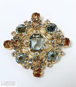 Schreiner diamond shaped radial pin elongated hexagon center stone 4 large round cab 4 flower head of 6 chatons surrounding 1 chaton 8 small baguette 4 small round cab clear champagne small baguette smoky blue large faceted chaton blue small inverted small inverted crystal faceted round topaz goldtone jewelry
