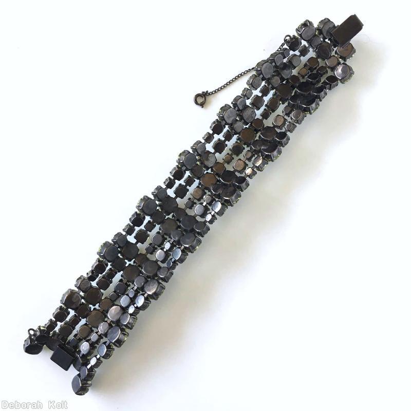Schreiner diamond shaped radial pin elongated hexagon center stone 4 large round cab 4 flower head of 6 chatons surrounding 1 chaton 8 small baguette 4 small round cab gray moonglow large round cab white moonglow round cab smoky small baguette smoky small chaton silverton jewelry