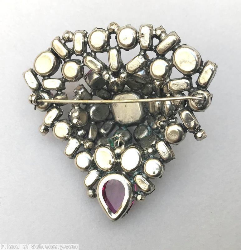 Schreiner domed triangle shaped pin large square stone center 1 large teardrop small baguette 4 surrounding small baguette 2 surrounding oval stone 4 surrounding chaton ice blue square faceted stone crystal baguette fuchsia purple faceted inverted jewelry