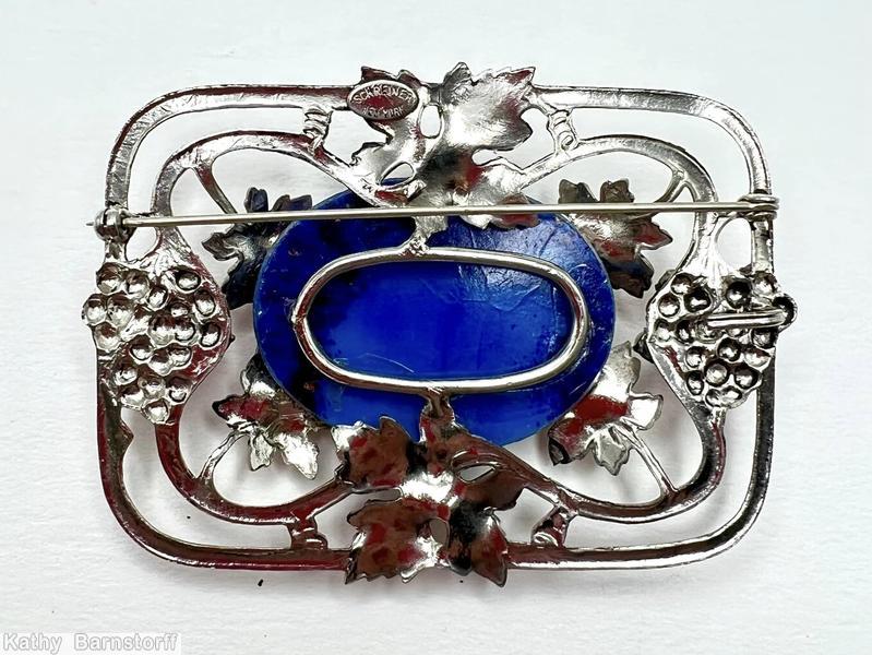 Schreiner rectangle metal deco grape pin 6 molded metal grape leaf covered large oval cab center 2 groups of 4 small round cab 2 groups of 13 small round stone 8 metal wire border with marks large oval lapis cab center red small round cab small faux pearl molded large grape leaf silvertone jewelry