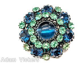 Schreiner round domed pin large round cab center 12 surrounding small chaton 7 large chaton large blue cab center green small chaton blue large chaton silvertone jewelry