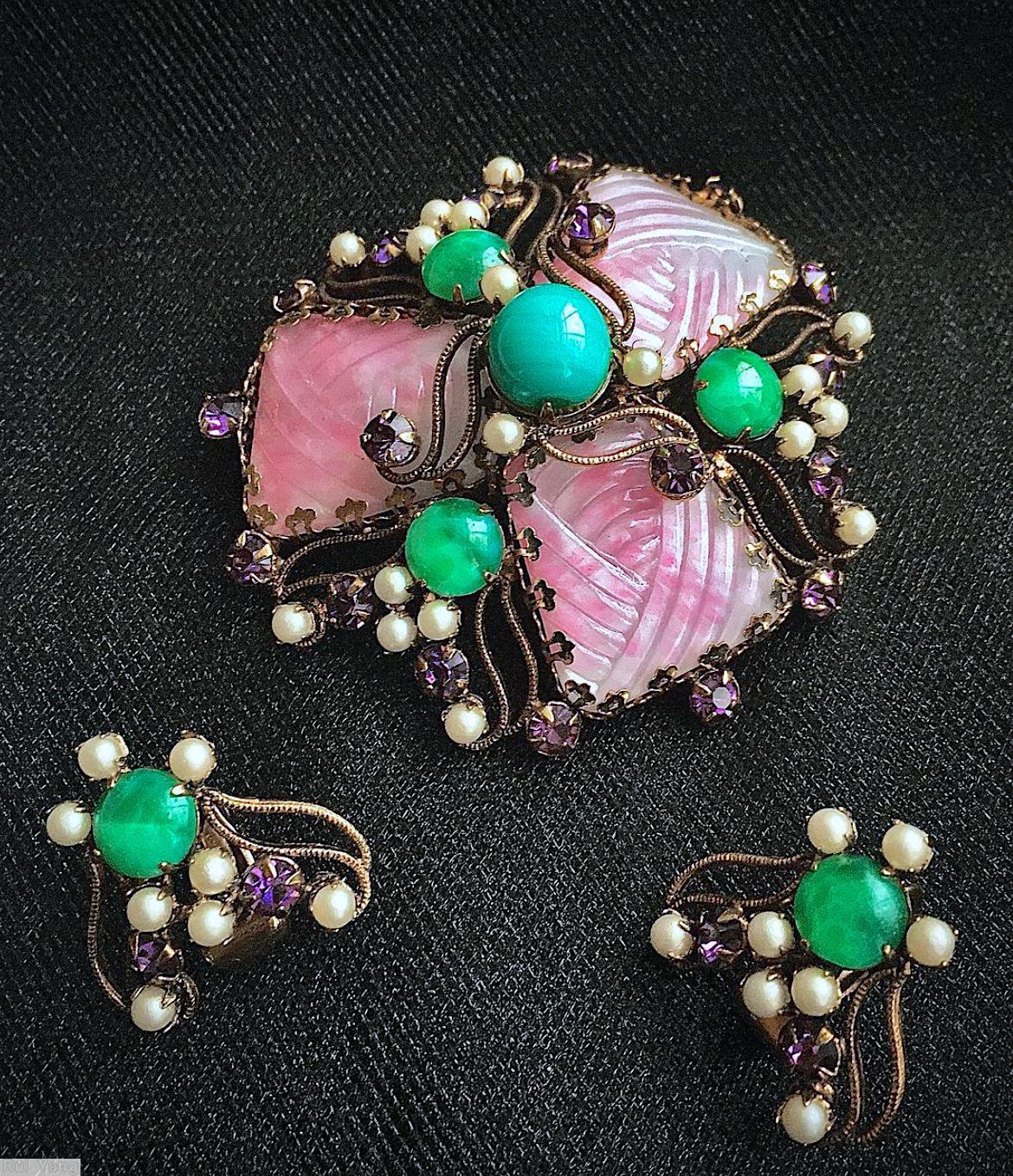Schreiner triangle domed radial pin 3 surrounding large molded marbled tapezoid stone scrollwork 3 chatong 1 large round cab center 3 small surrounding pearl 18 small seeds pearl 18 small chaton pink marbled molded tapezoid stone peking glass round cab purple small chaton goldtone jewelry