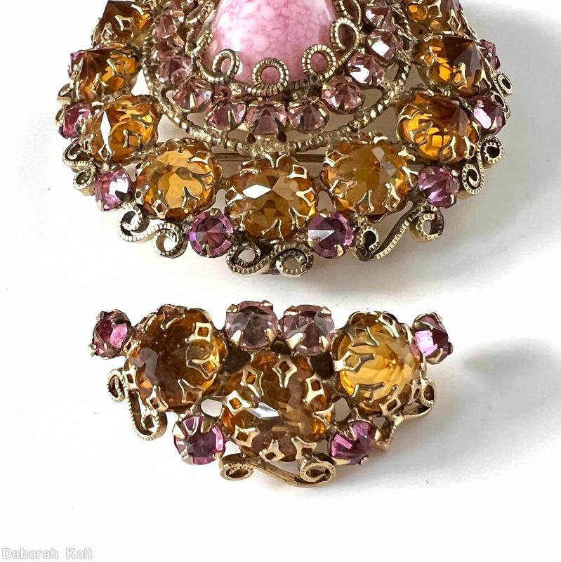 Schreiner oval shaped radial domed pin large oval stone center with scrollwork prong 19 surrounding chaton 2nd round 13 large inverted stone scrollwork border pink white marbled large oval cab center clear peach small inverted stone large clear inverted topaz goldtone jewelry