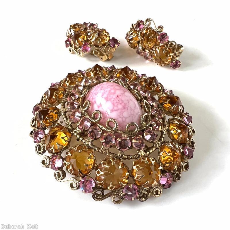 Schreiner oval shaped radial domed pin large oval stone center with scrollwork prong 19 surrounding chaton 2nd round 13 large inverted stone scrollwork border pink white marbled large oval cab center clear peach small inverted stone large clear inverted topaz goldtone jewelry